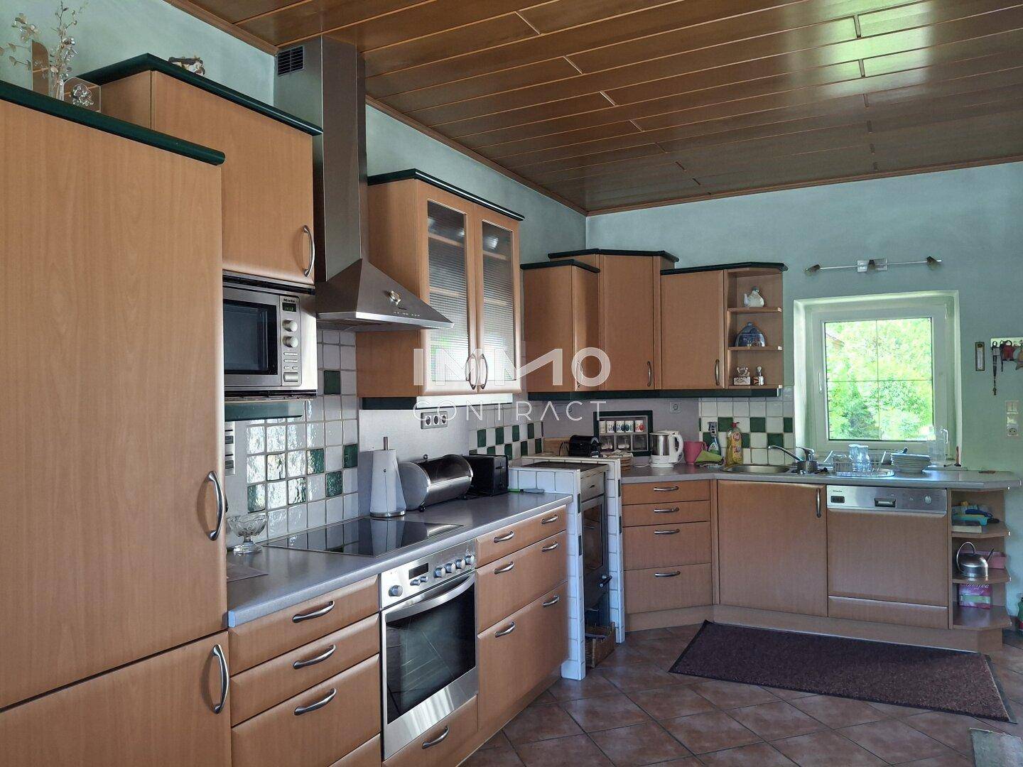Funktionale Küche mit Holzschränken, Fliesenrückwand und modernen Geräten.