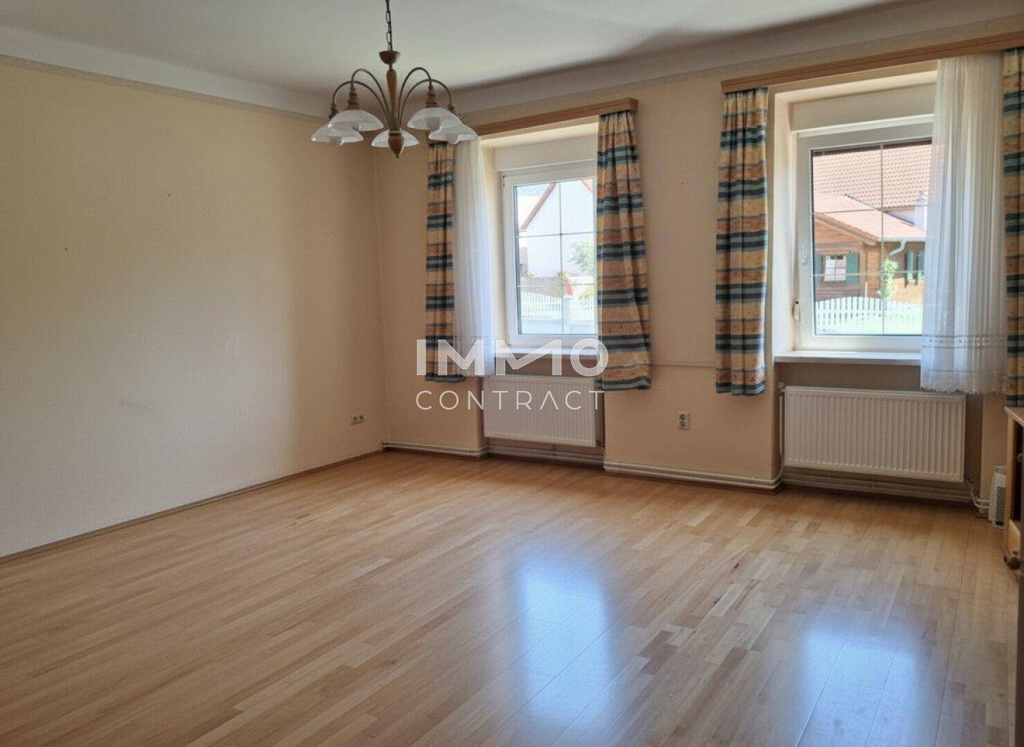Helles Wohnzimmer mit Holzboden, großen Fenstern und traditionellem Kronleuchter.