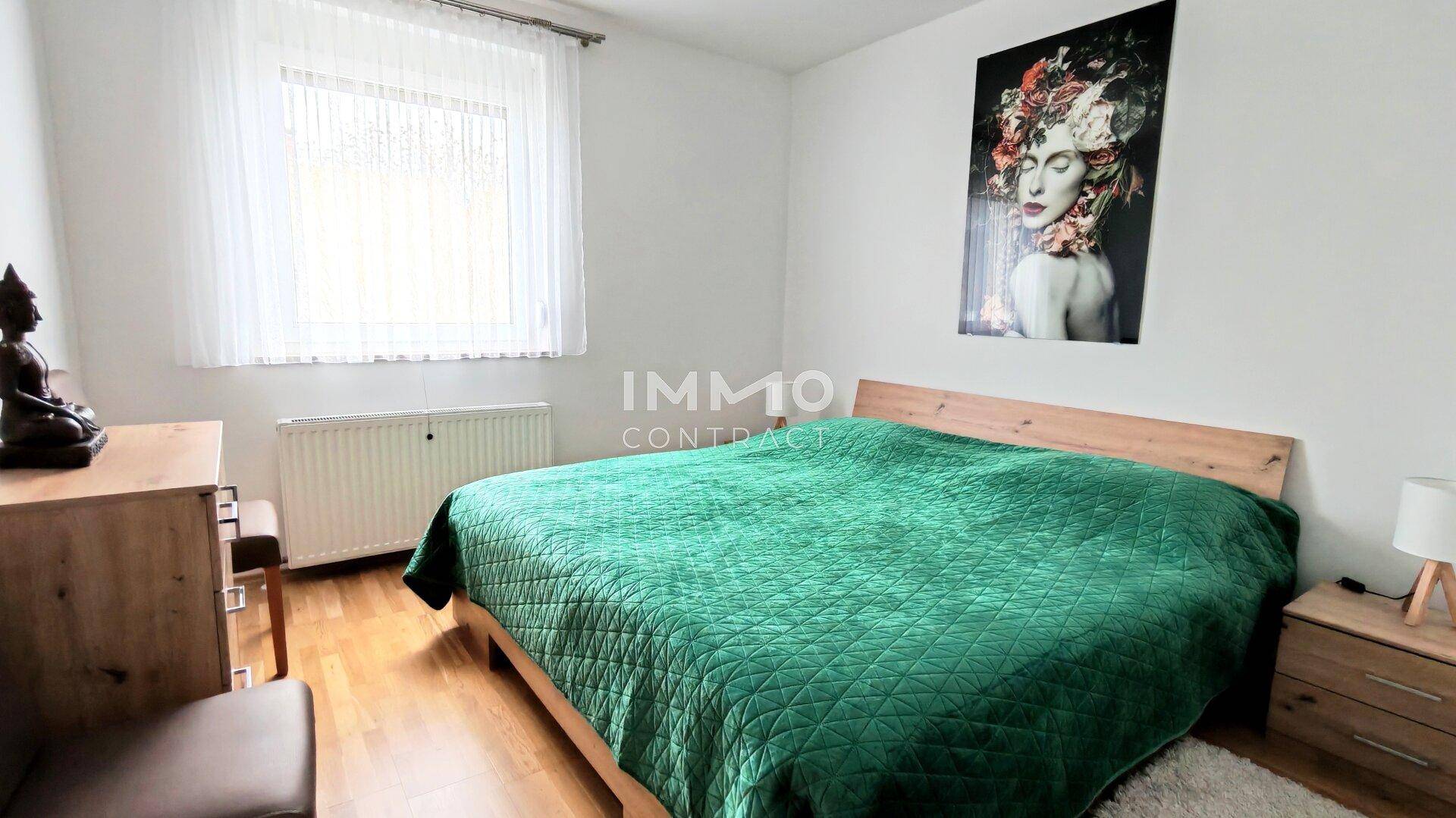 Gemütliches Schlafzimmer mit Holzbett, Parkettboden und Fenster für angenehmes Tageslicht.