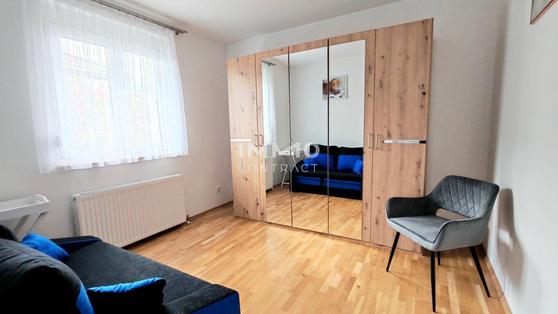 Schlafzimmer mit bequemer Schlafcouch, großem Spiegelschrank und hellem Holzboden.