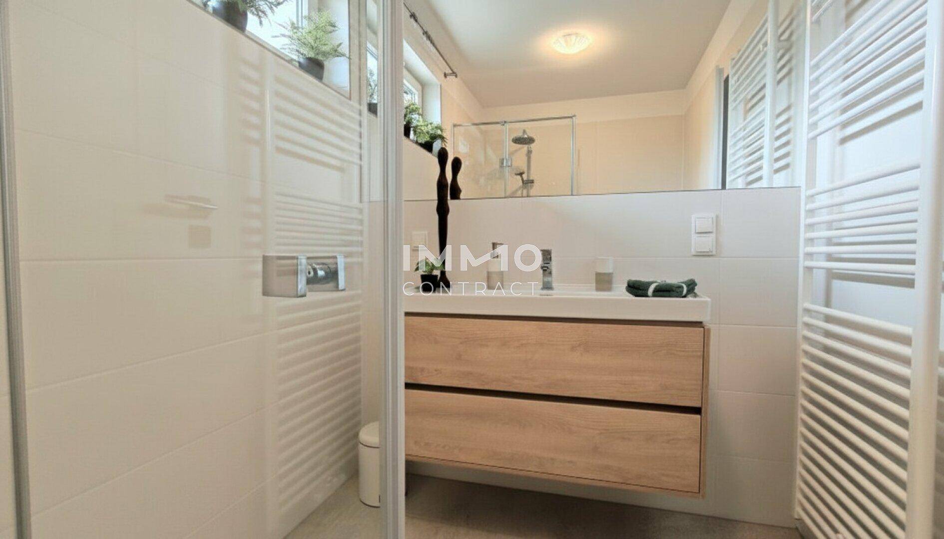 Modernes Badezimmer mit Dusche, Einzelwaschbecken und beheiztem Handtuchhalter.