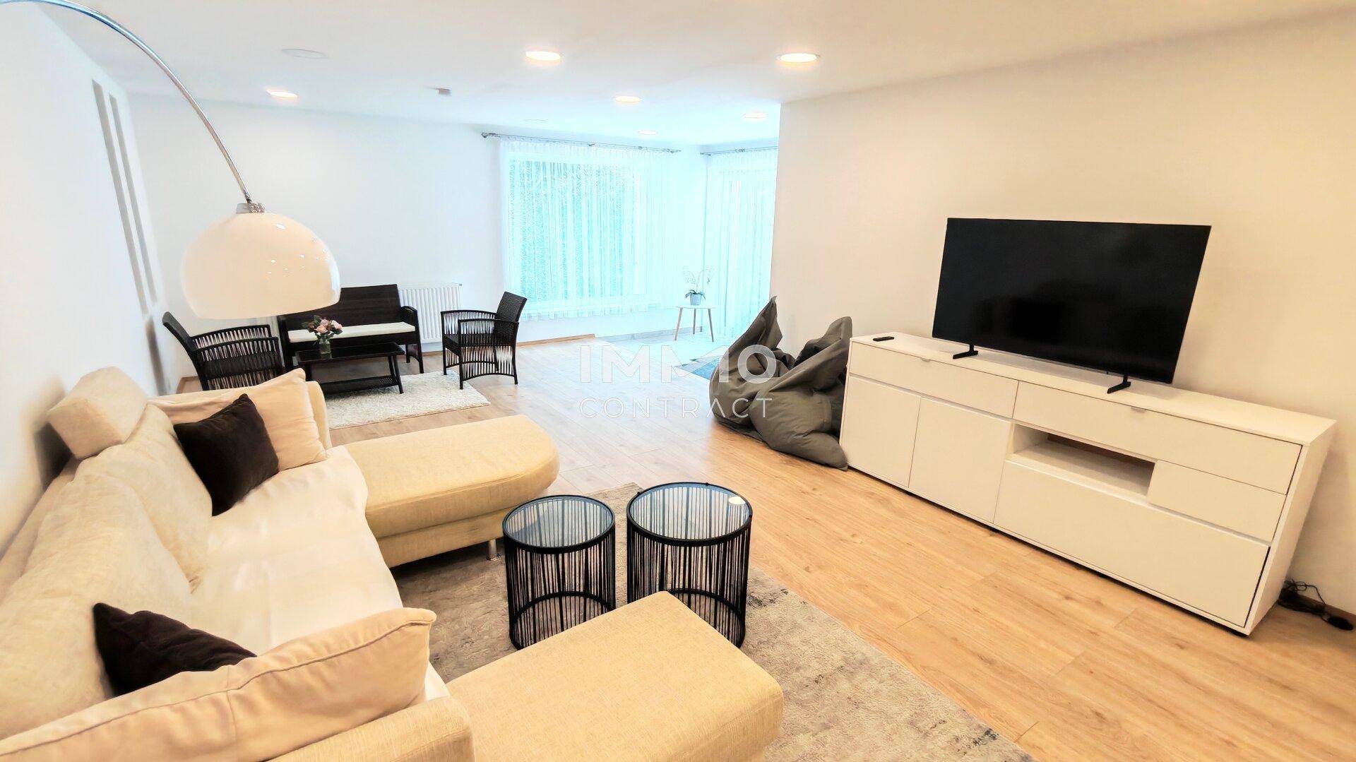 Großzügiges Wohnzimmer mit bequemer Couch, Fernseher und Blick auf den Essbereich.