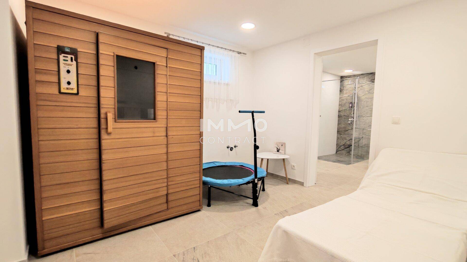 Privater Wellnessbereich mit Sauna, Fitnessgeräten und angrenzender Dusche für Entspannung.