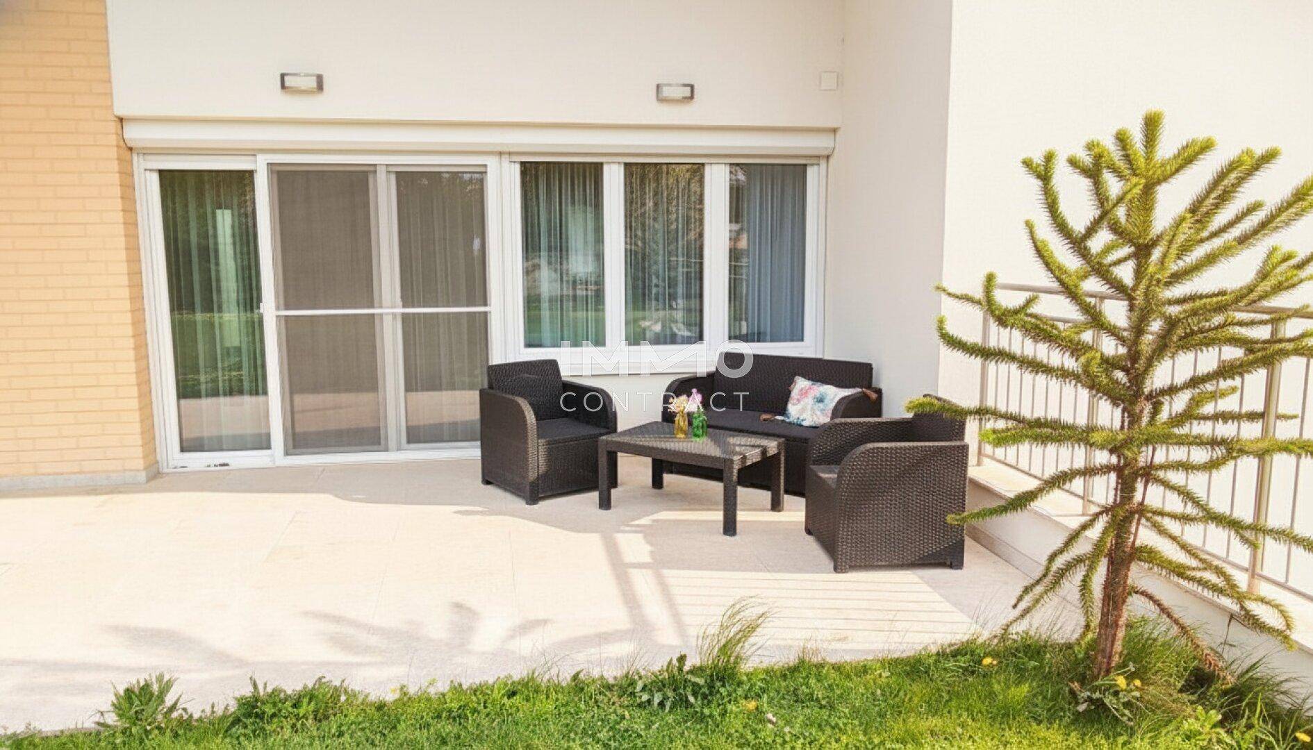Sonniger Terrassenbereich mit Gartenmöbeln und direktem Zugang zum Haus durch große Schiebetüren.