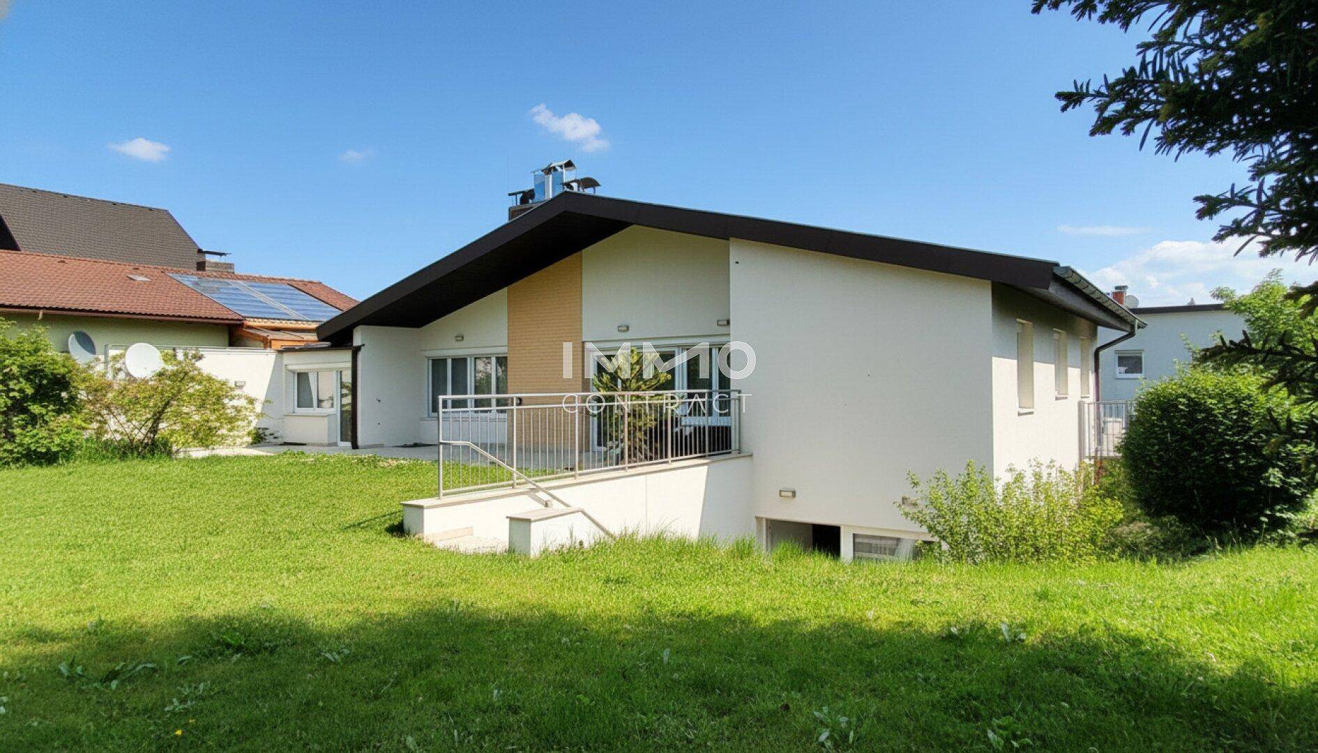 Seitenansicht des Hauses mit gepflegtem Rasen und Zugang zum Untergeschoss.