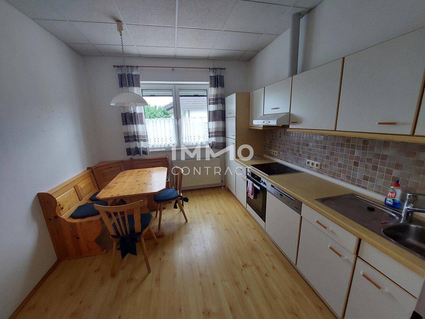 Gemütliche Wohnküche mit Holztisch, Eckbank und Einbauküche mit Fensterblick.