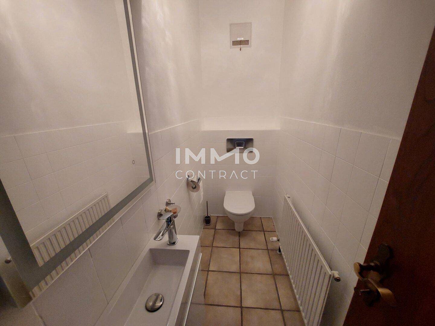 Kleines Gäste-WC mit Waschbecken, Toilette und Fliesenboden.