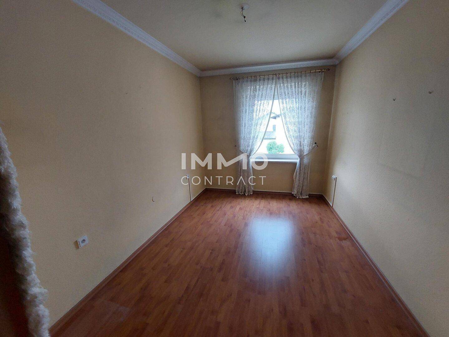 Kleines Schlafzimmer mit Laminatboden, gelben Wänden und einem Fenster.