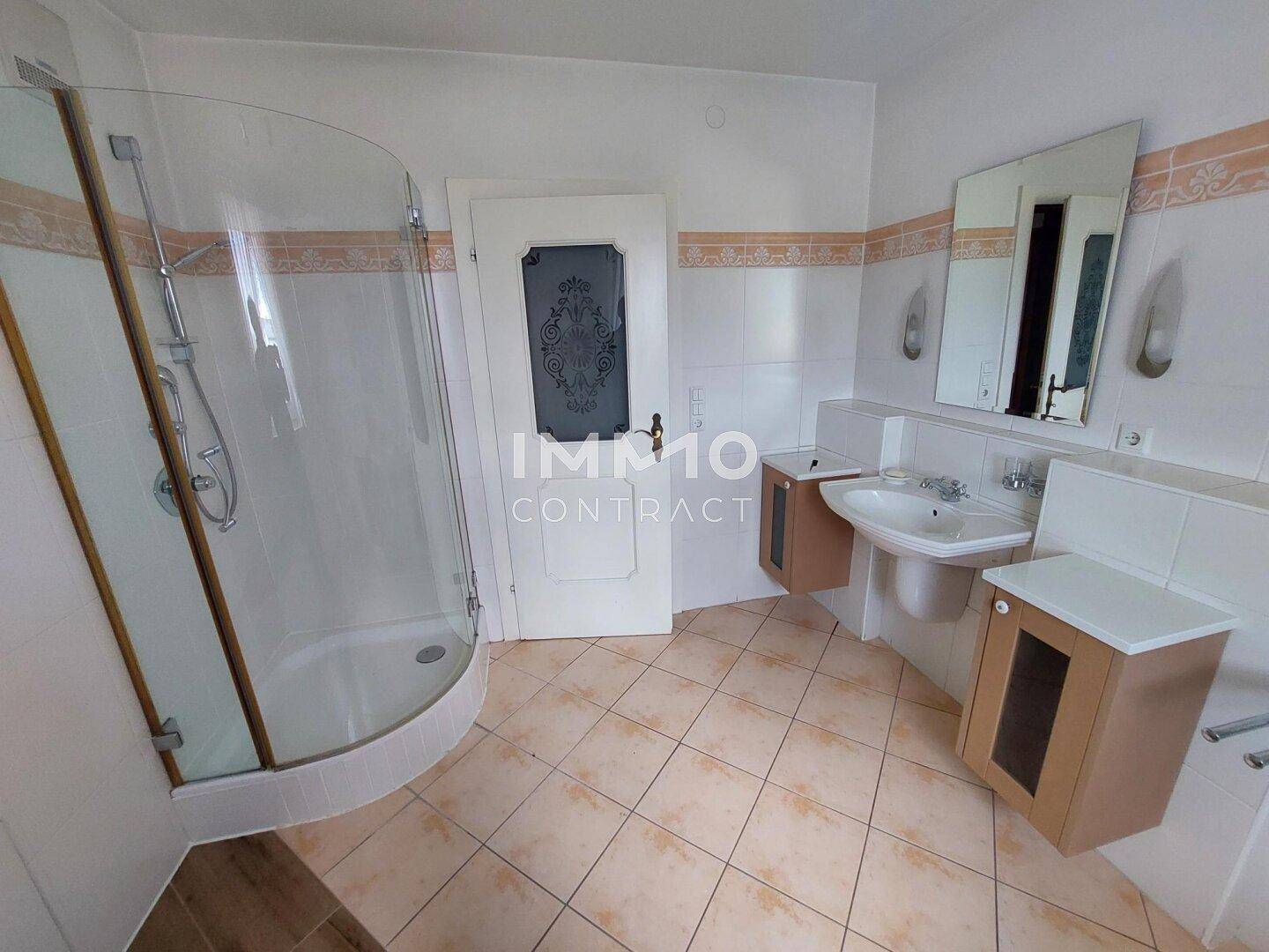 Geräumiges Badezimmer mit Duschkabine, Waschbecken und Fliesenboden.