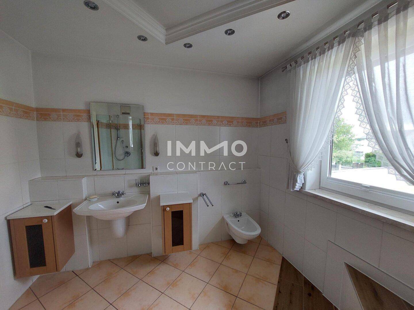 Helles Badezimmer mit Waschbecken, Bidet, Fenster und Fliesenboden.