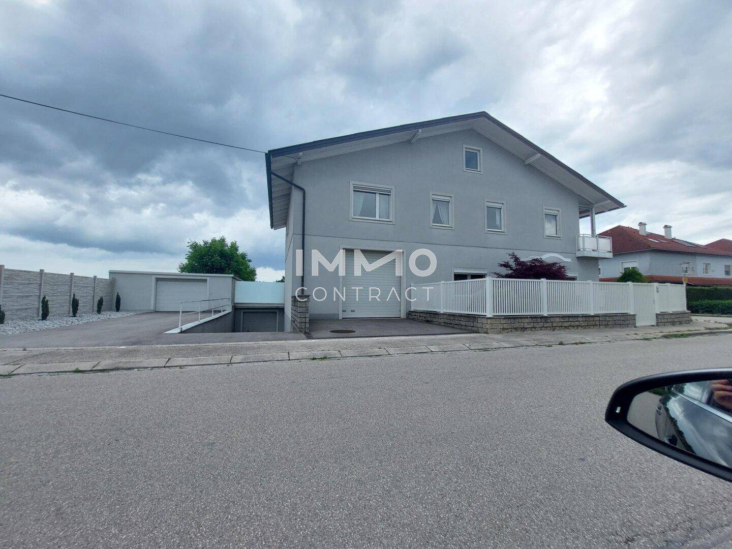 Ansicht des Einfamilienhauses von der Straße mit Garage und Zufahrt.