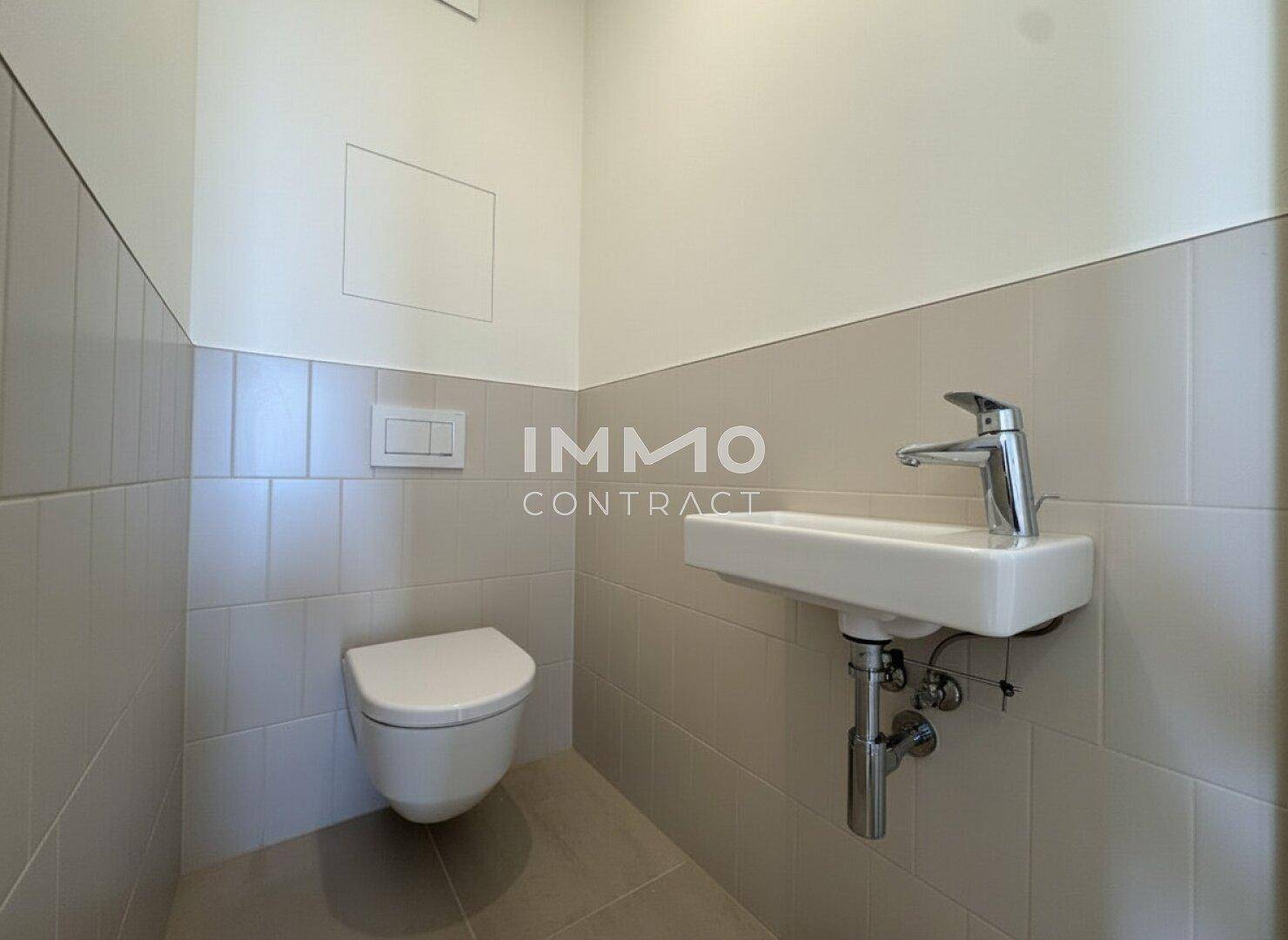 Modernes Gäste-WC mit Wand-WC und kleinem Waschbecken, halbhoch gefliest.