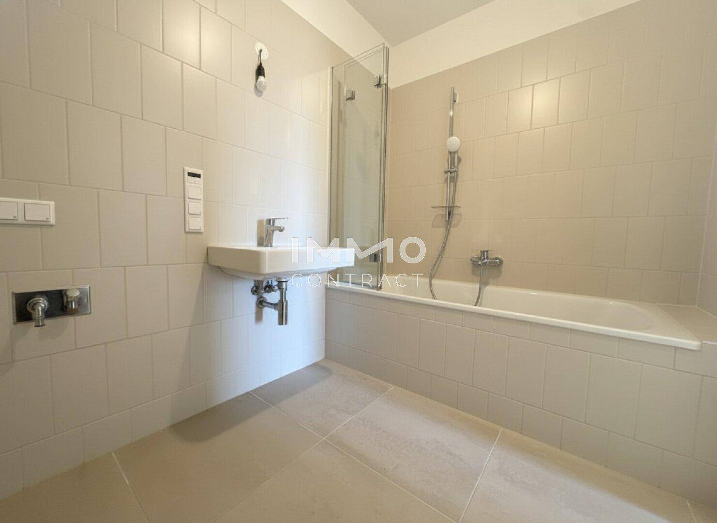 Helles Badezimmer mit Badewanne, Duschabtrennung und modernem Waschbecken.