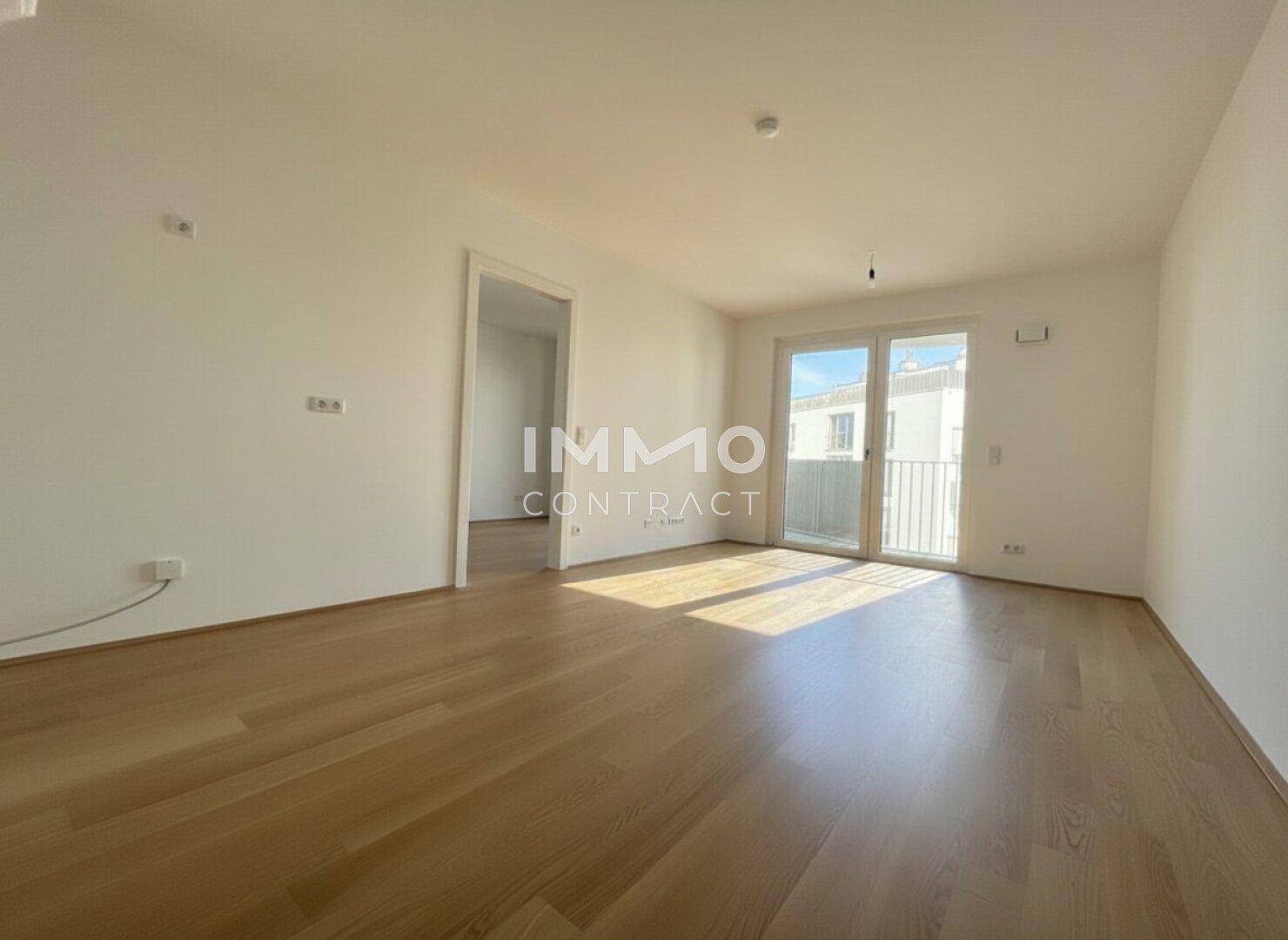 Heller, leerer Wohnraum mit Eichenparkettboden und Zugang zu einem Balkon.