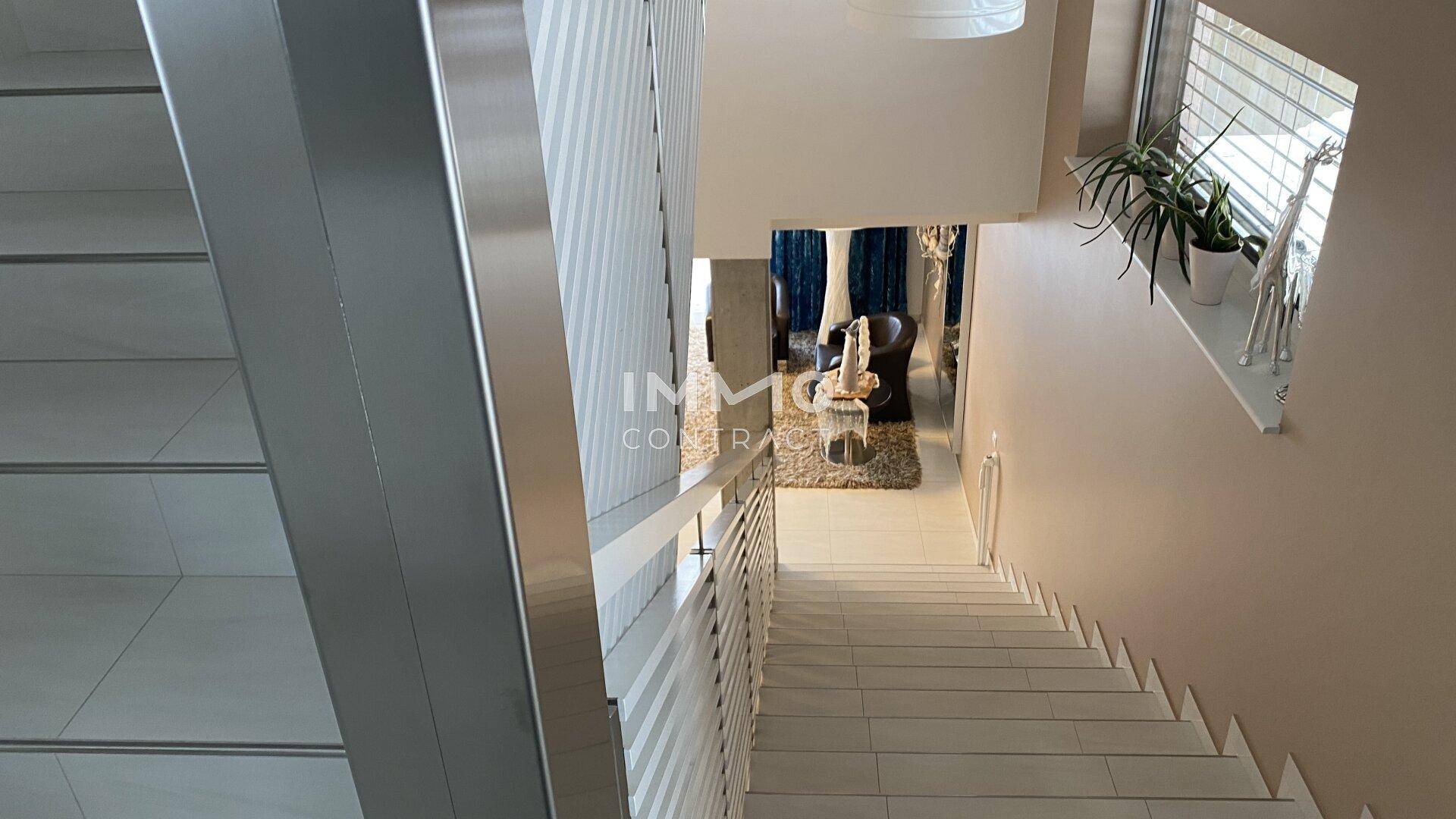 Heller Treppenbereich mit modernen Geländern und Blick in den unteren Wohnbereich des Hauses.