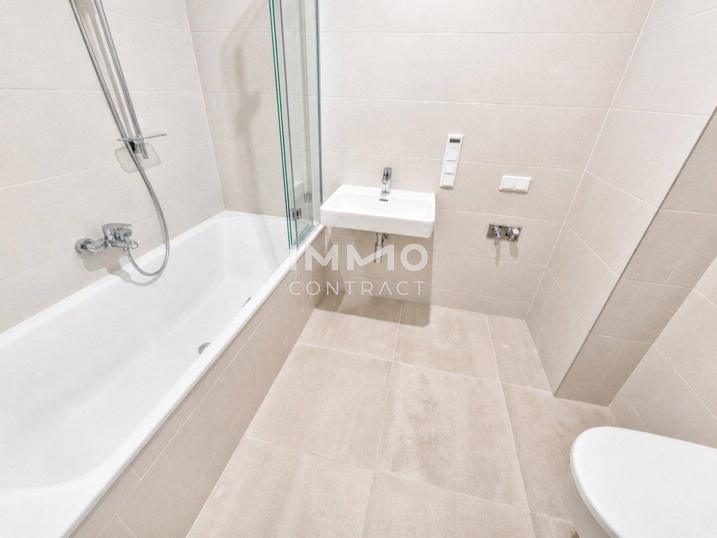 Modernes Badezimmer mit Badewanne, Waschbecken und hellen Fliesen in neuwertigem Zustand.
