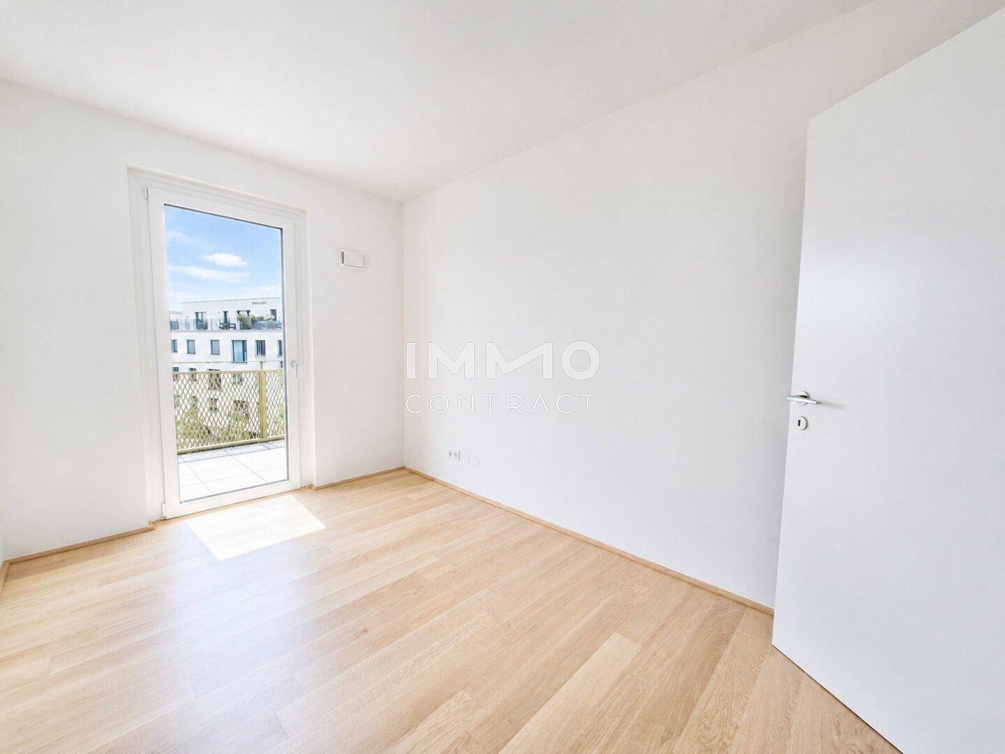 Weiteres helles Schlafzimmer mit Parkettboden und Fenstertür, die zu einem Balkon führt, ideal für Ruhe.
