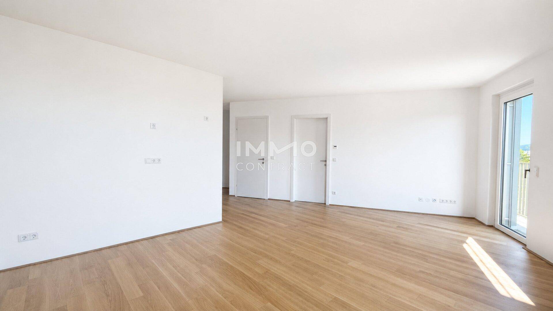 Leerer, heller Raum mit Parkettboden und Zugang zu einem Außenbereich.