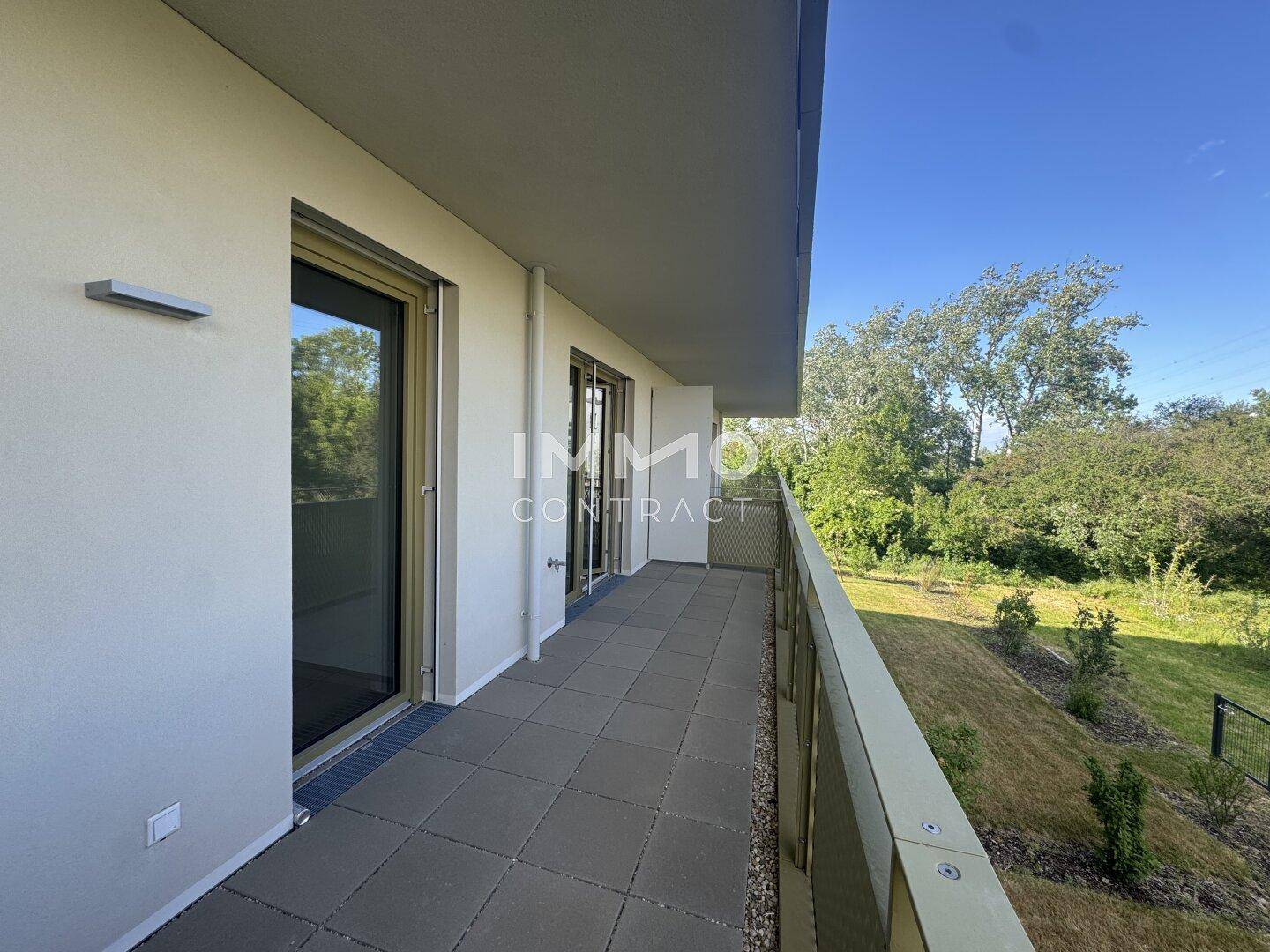 Langer Balkon mit Fliesenboden und weitem Blick ins Grüne.