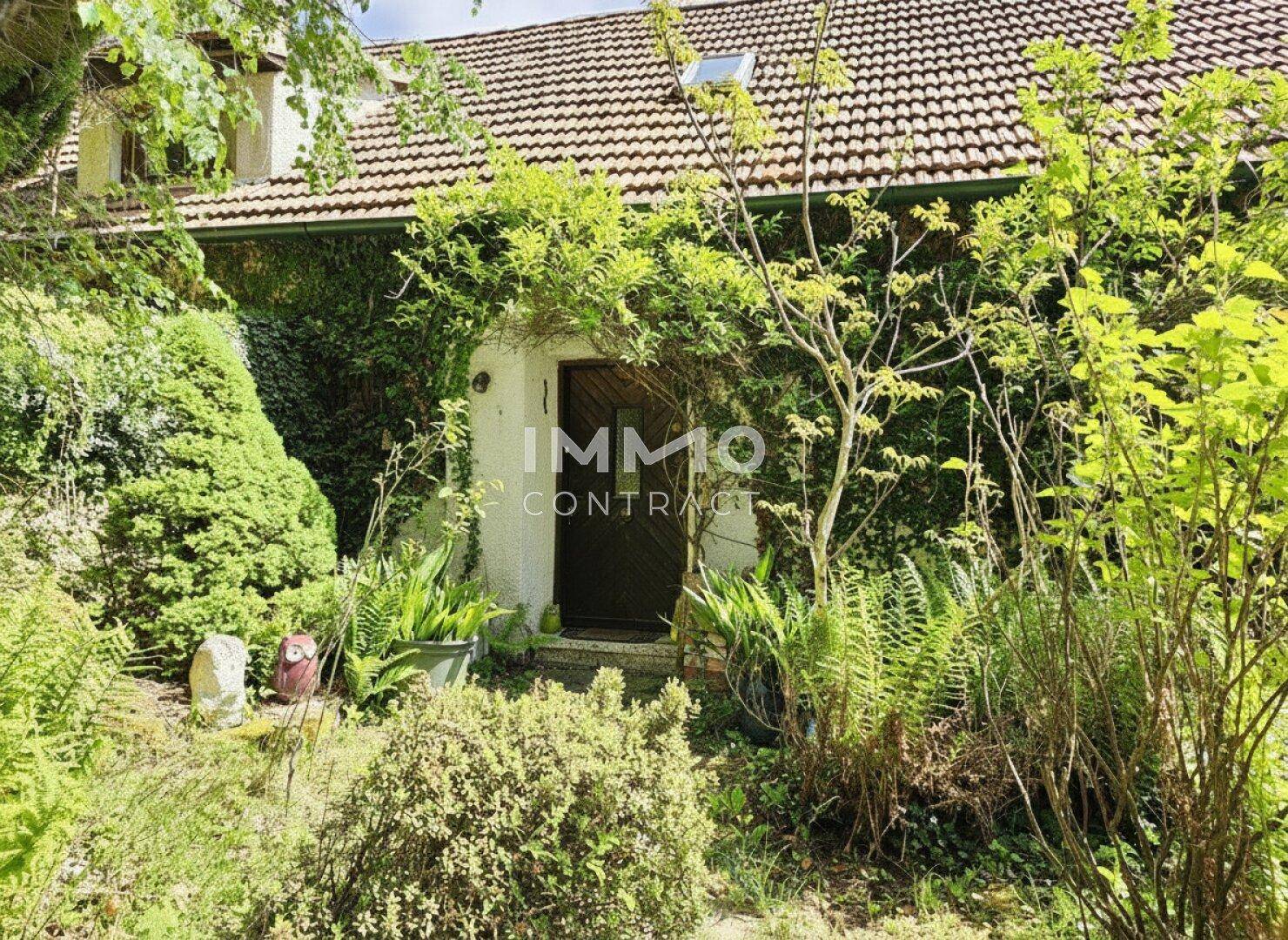 Eingangsbereich des Hauses, umgeben von üppiger Bepflanzung und einem kleinen Garten.