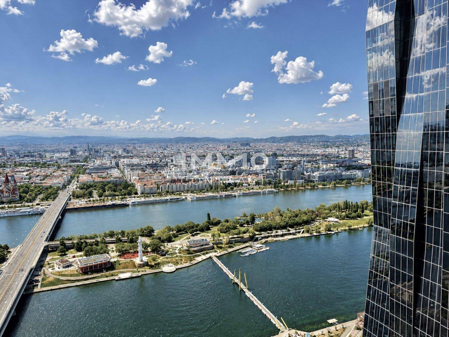 Panoramablick auf die Stadt mit Fluss, Brücken und umliegender Landschaft unter blauem Himmel.