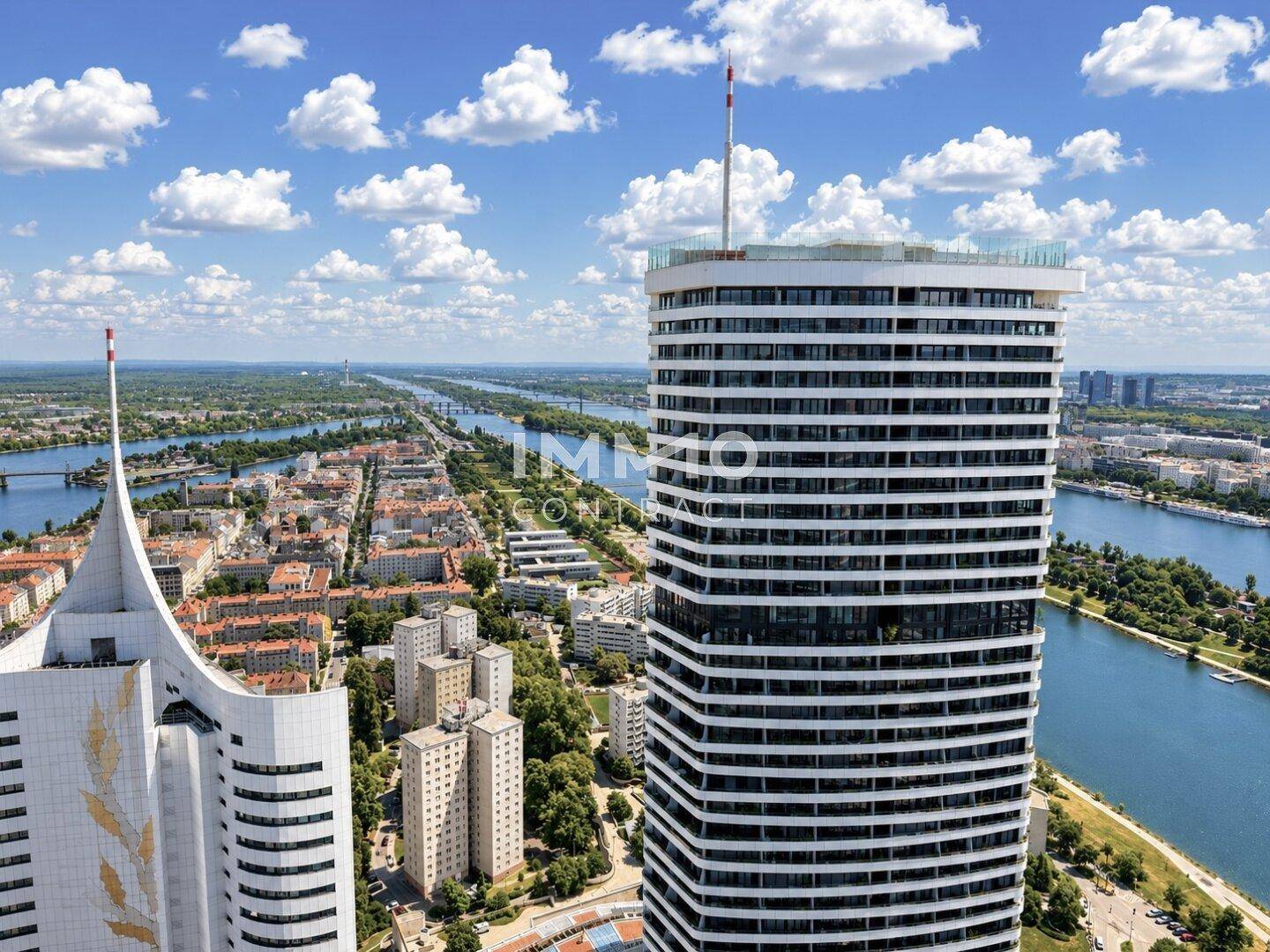 Luftaufnahme von zwei markanten Hochhäusern mit Fluss und Stadtlandschaft im Hintergrund.