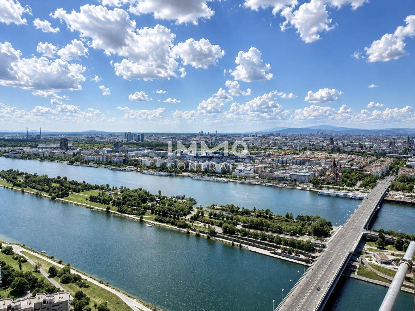 Weitläufiger Blick auf den Fluss mit Brücken und der städtischen Skyline unter einem klaren blauen Himmel.