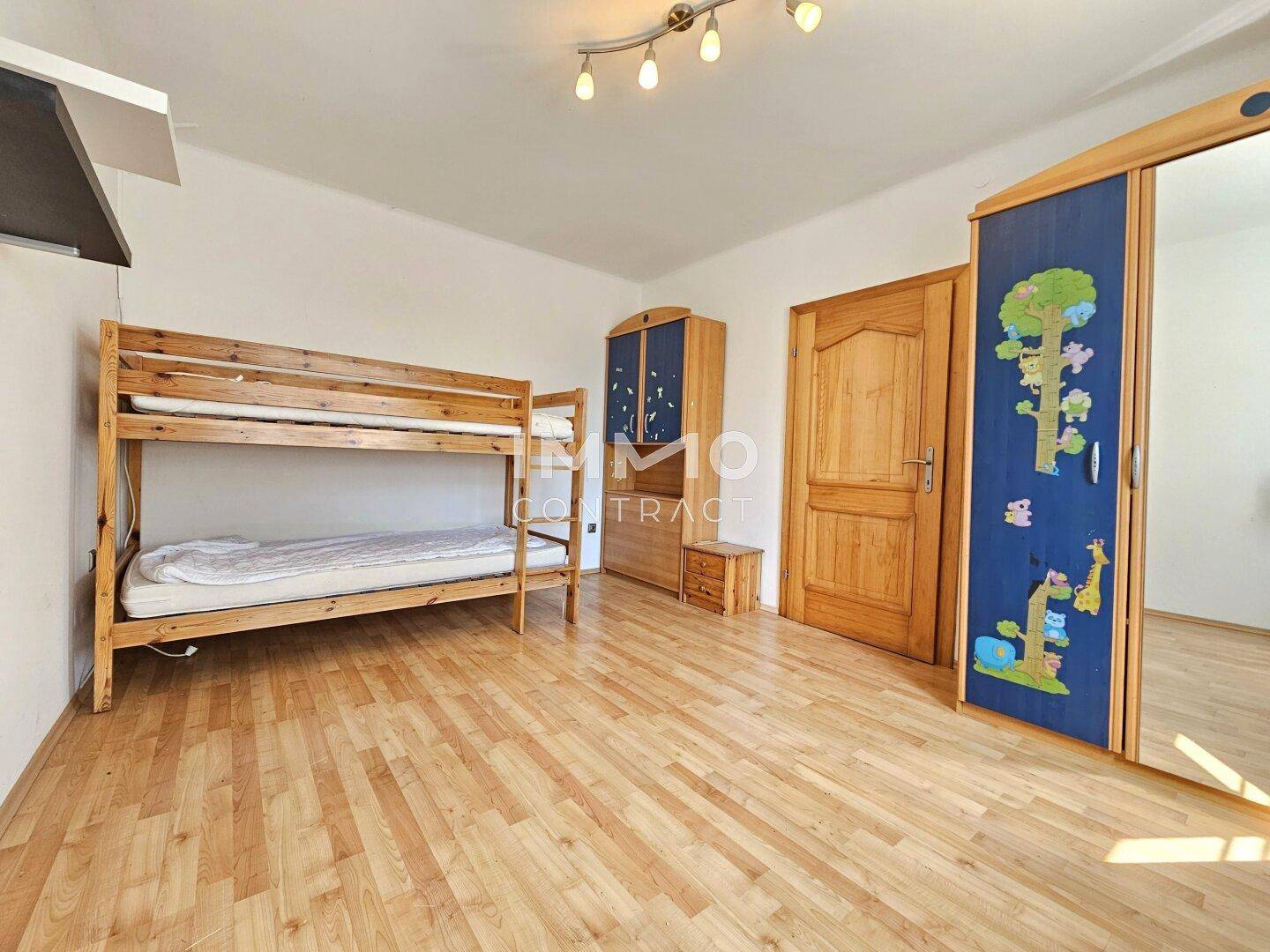 Kinderzimmer mit Etagenbett, Laminatboden und farbenfrohem Schrank, ideal für Geschwister.