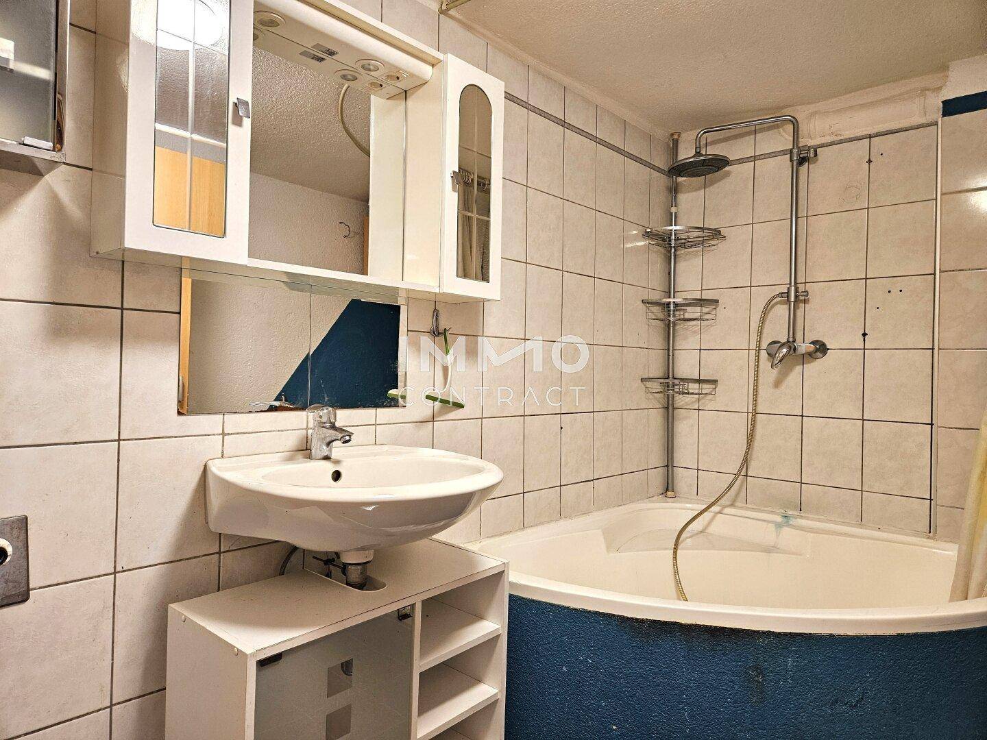 Badezimmer mit Eckbadewanne, Waschbecken und weißen Fliesen, ausgestattet mit Duschfunktion.