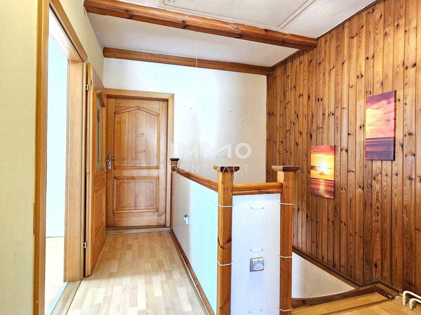 Flur im Obergeschoss mit Holzvertäfelung, Holzbalken und Zugang zu den Zimmern.