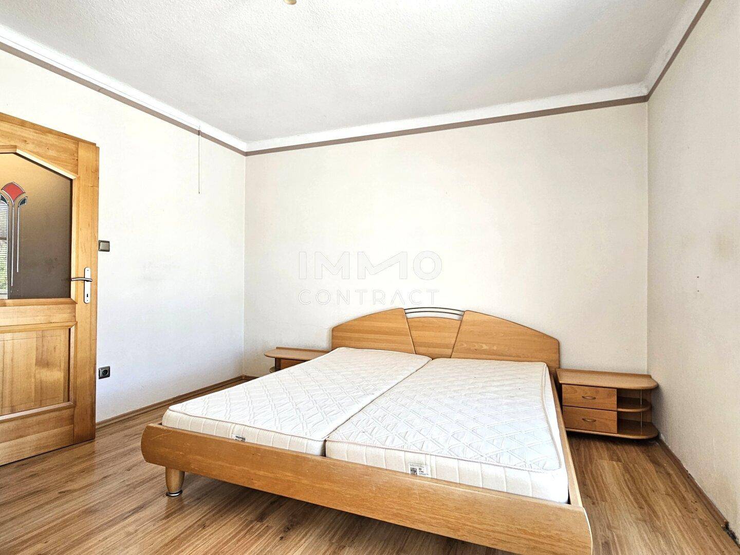 Schlafzimmer mit Doppelbett, Laminatboden und schlichter Einrichtung, bietet Ruhe und Komfort.