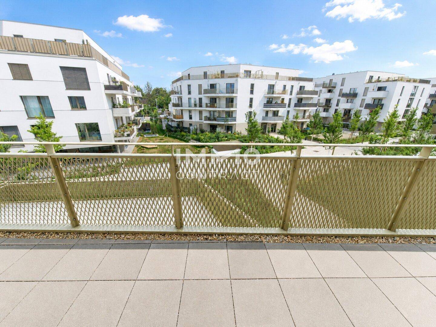 Großer Balkon mit Fliesenboden und weitem Blick auf die moderne Wohnanlage.