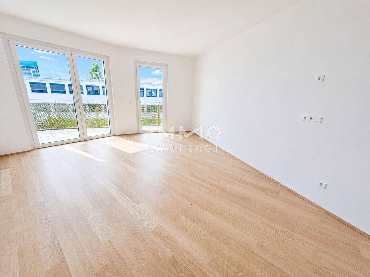 Lichtdurchfluteter Raum mit großen Fenstern und Holzboden, bereit zur individuellen Einrichtung.