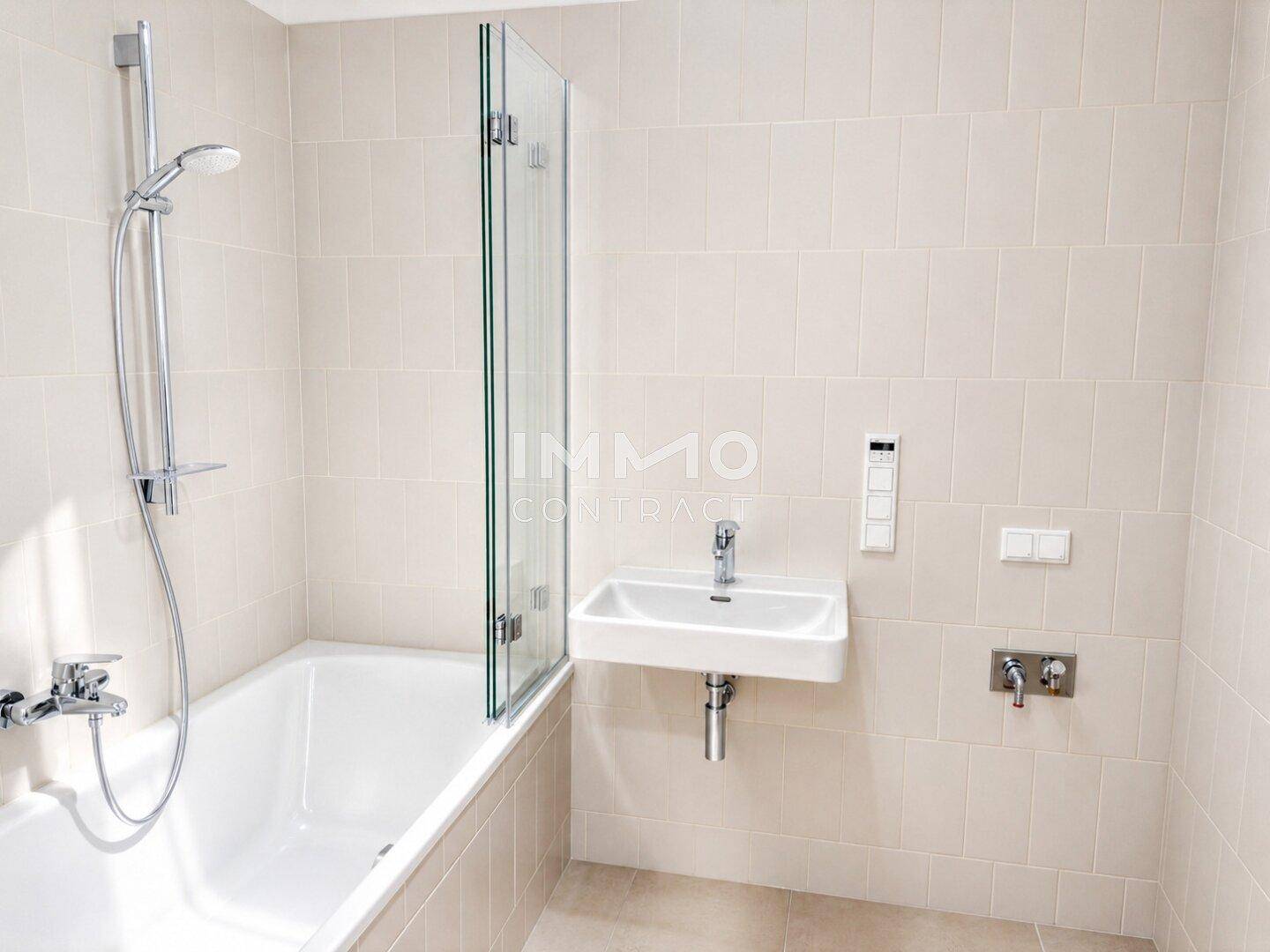 Modernes Badezimmer mit hellen Fliesen, Badewanne mit Duschwand und Einzelwaschbecken.
