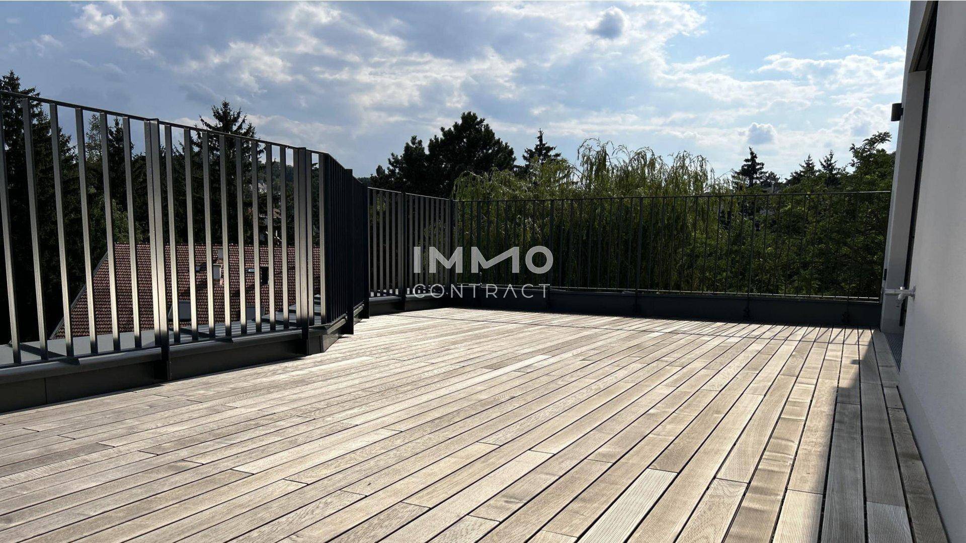 Weitläufige Dachterrasse mit Holzbelag und Blick ins Grüne, ideal für Entspannung.