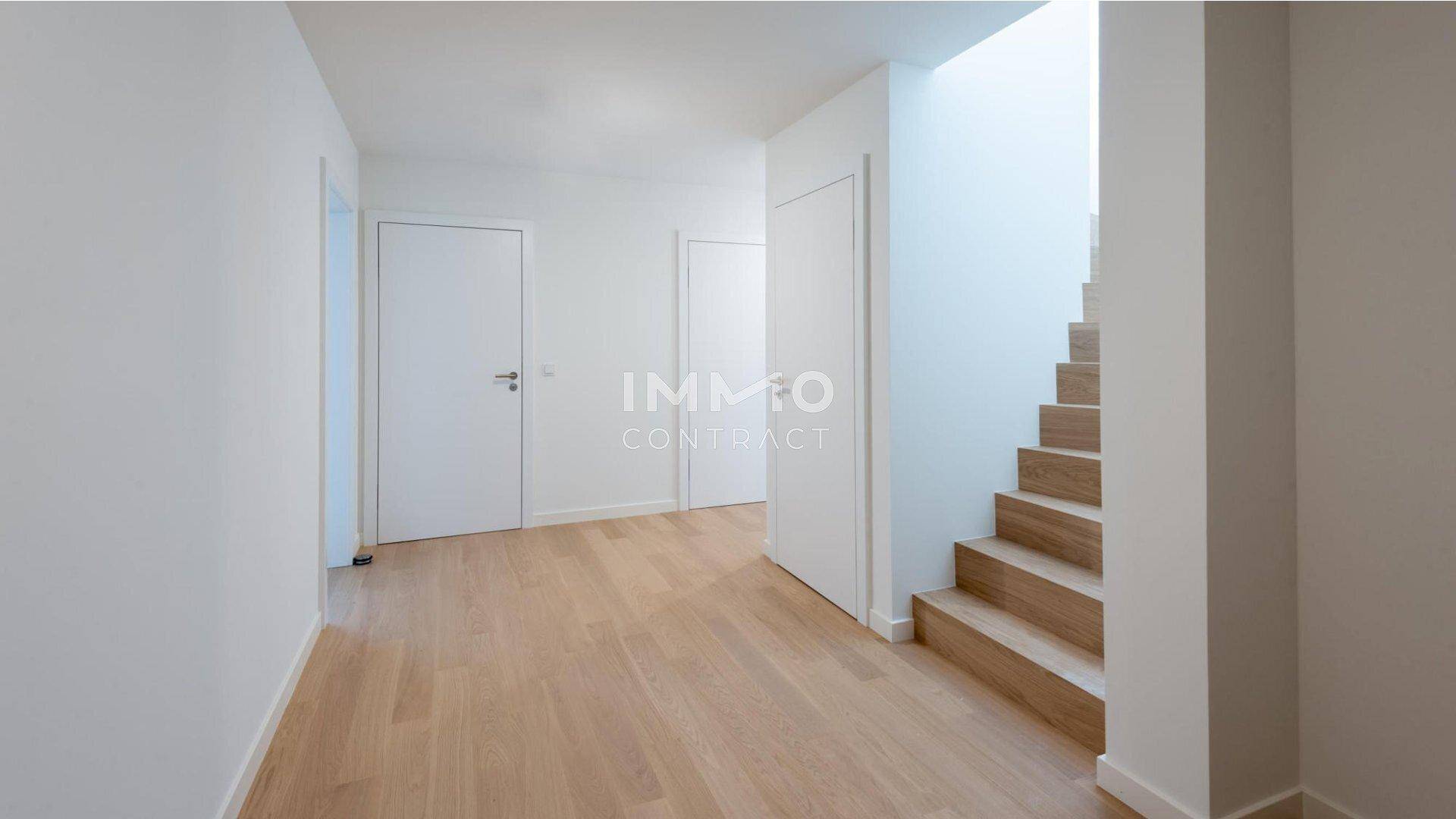 Heller Flur mit Holztreppe und Parkettboden, der zu weiteren Räumen führt.