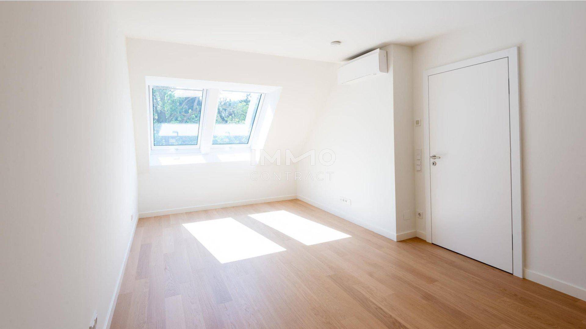 Helles Zimmer mit Dachschrägen, Parkettboden, Dachfenstern und Klimaanlage.