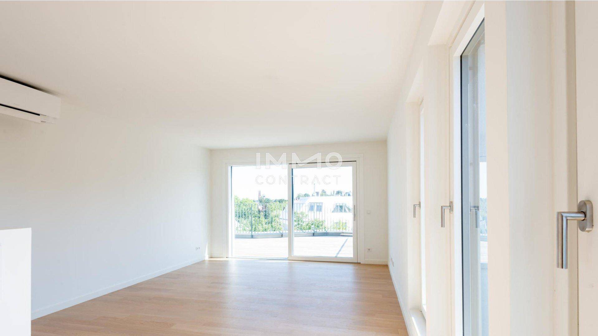 Heller Wohnraum mit Parkettboden, großem Fenster und Zugang zu einem Außenbereich.