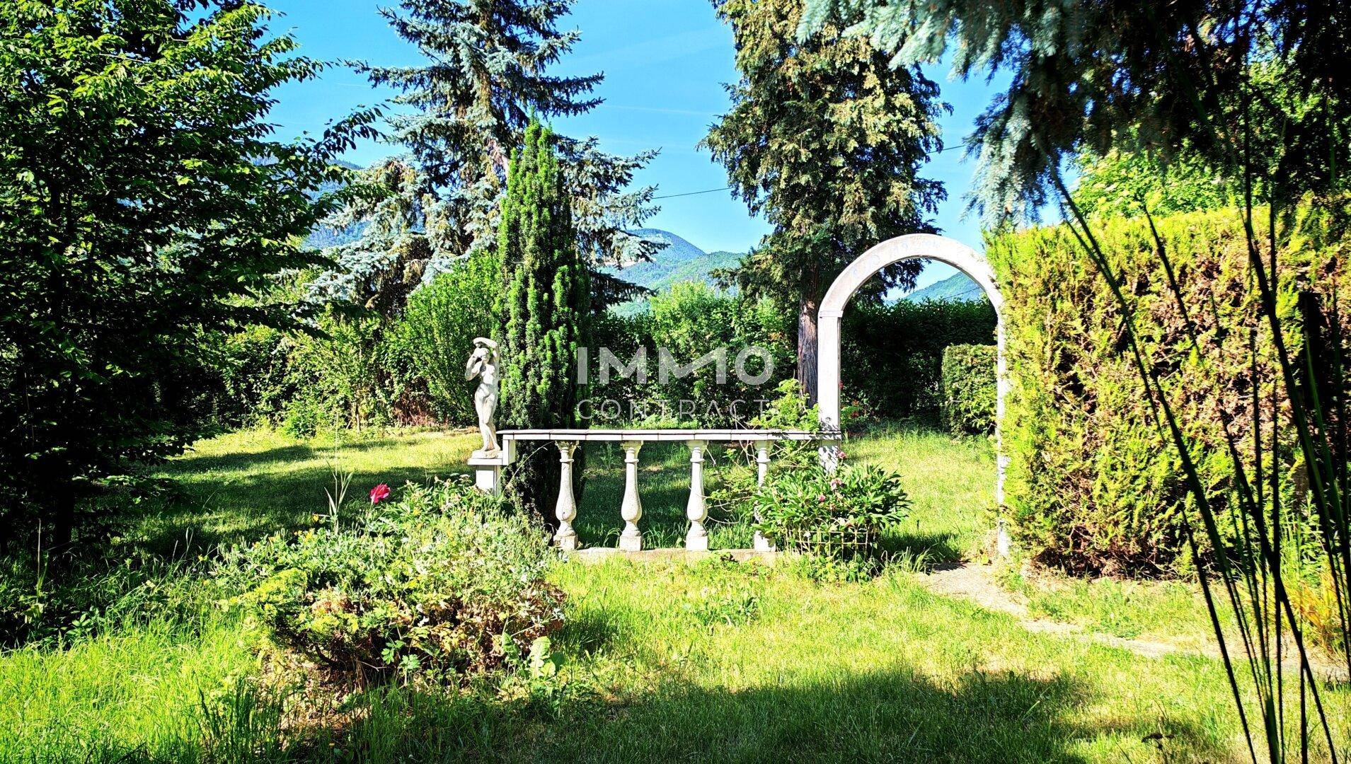 Idyllischer Gartenbereich mit Rasen, dekorativer Balustrade und Bergblick.