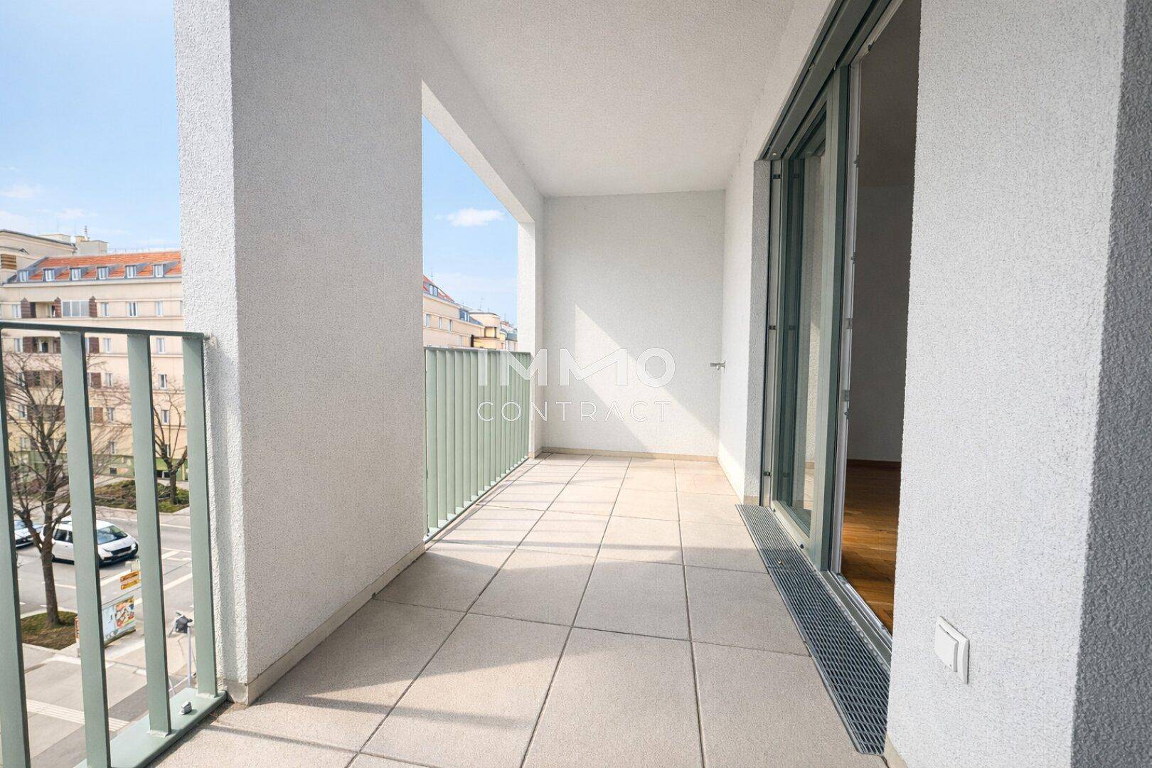 Geräumiger Balkon mit Fliesenboden und Blick auf die umliegende Stadtlandschaft.