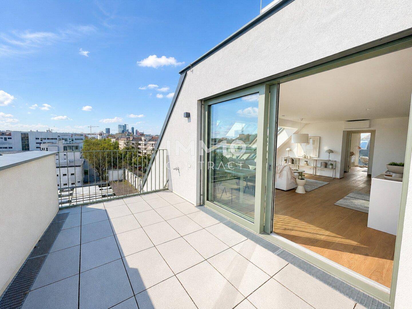 Heller Balkon mit Fliesenboden und Schiebetür, bietet Zugang zum Innenbereich und einen Ausblick auf die Stadt.