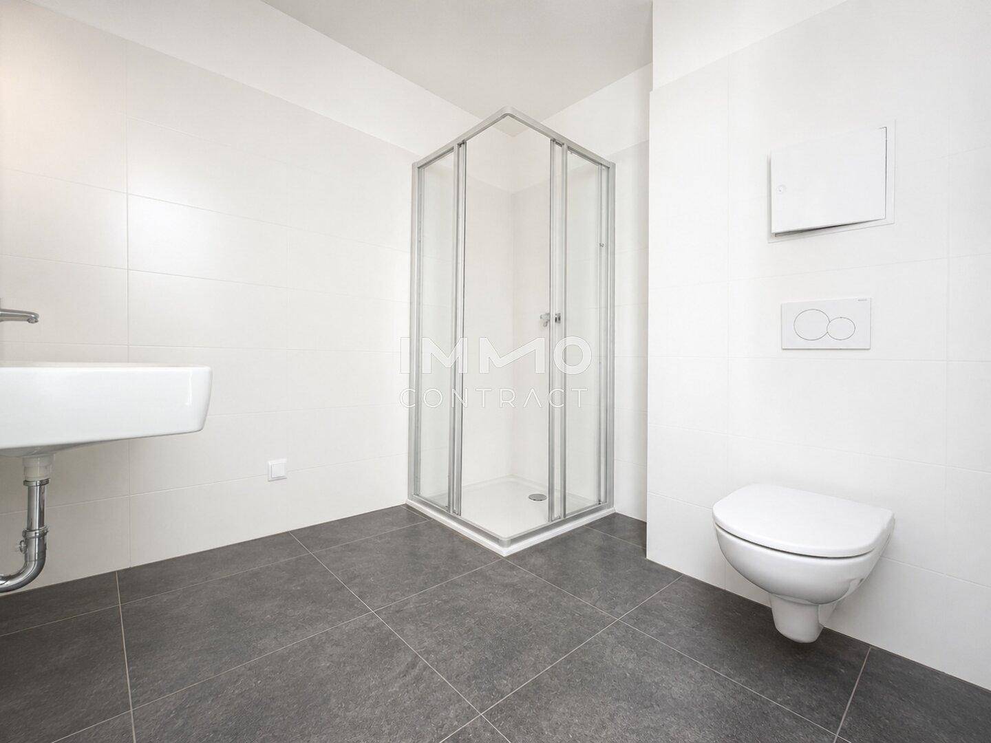 Modernes Badezimmer mit Duschkabine, wandhängendem WC und Waschbecken in Weiß und Grau.