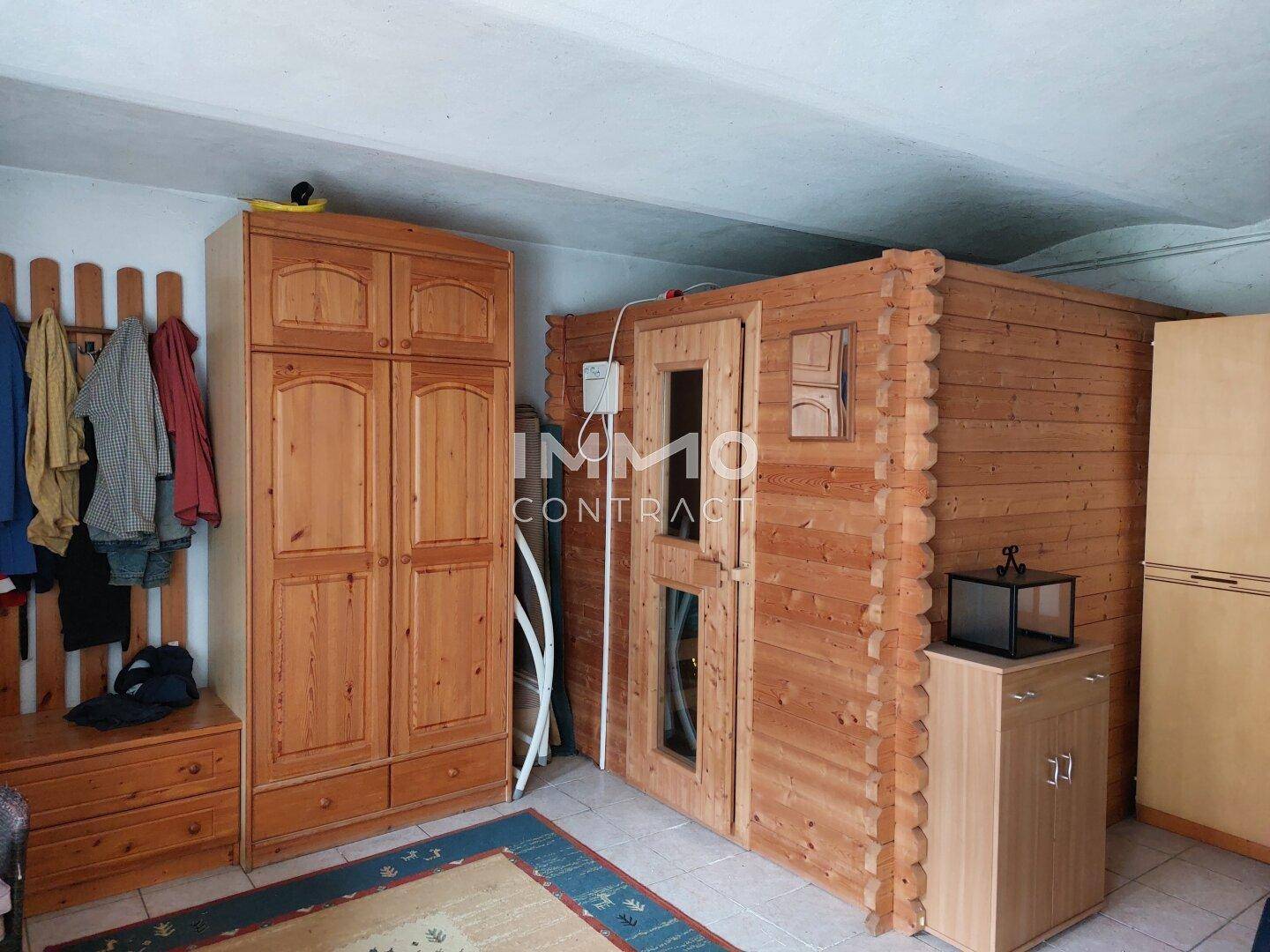 Geräumiger Innenraum mit einer Holzsauna, einem Kleiderschrank und Fliesenboden.