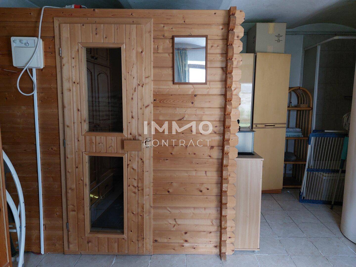 Nahaufnahme einer Holzsauna mit Glastür in einem gefliesten Raum.