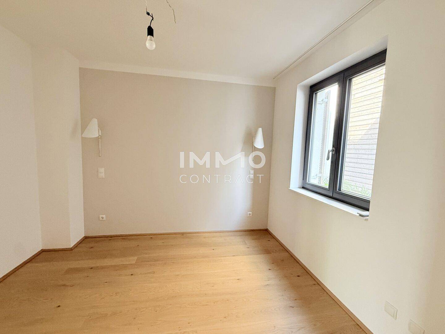 Helles Schlafzimmer mit Holzboden und zwei Wandleuchten, bereit zur individuellen Gestaltung.