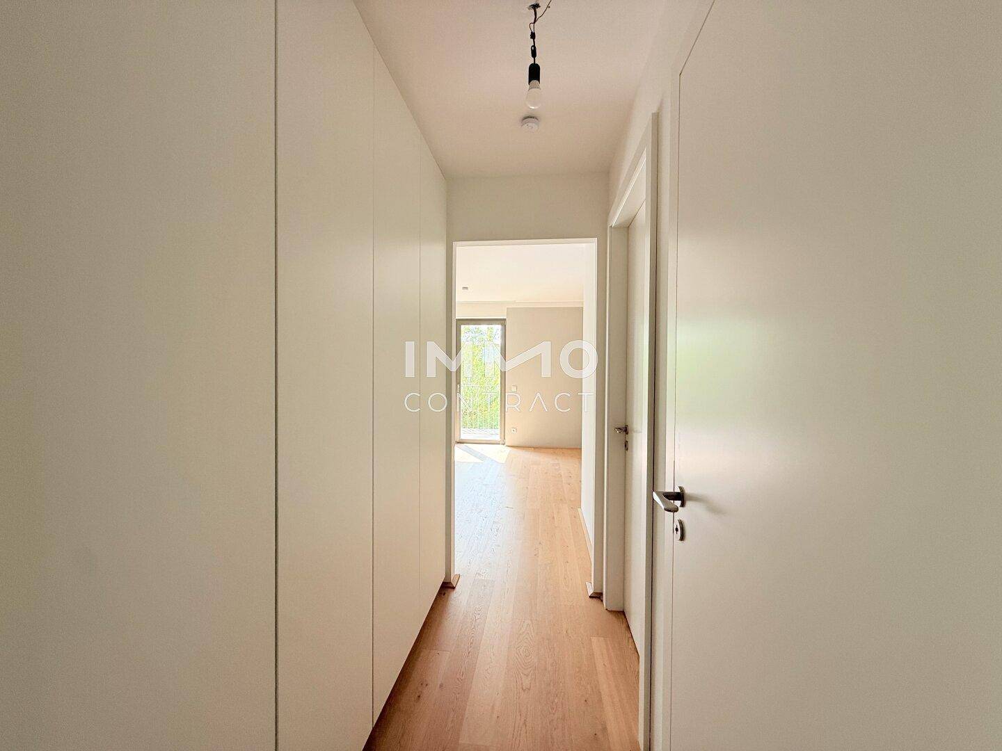 Heller Flur mit Holzboden und integrierten Schränken, führt zu weiteren Räumen.