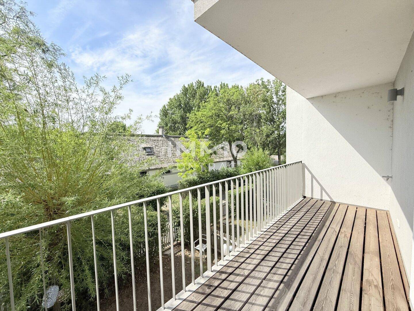 Geräumiger Balkon mit Holzboden und Blick auf die grüne Umgebung und Reetdächer.