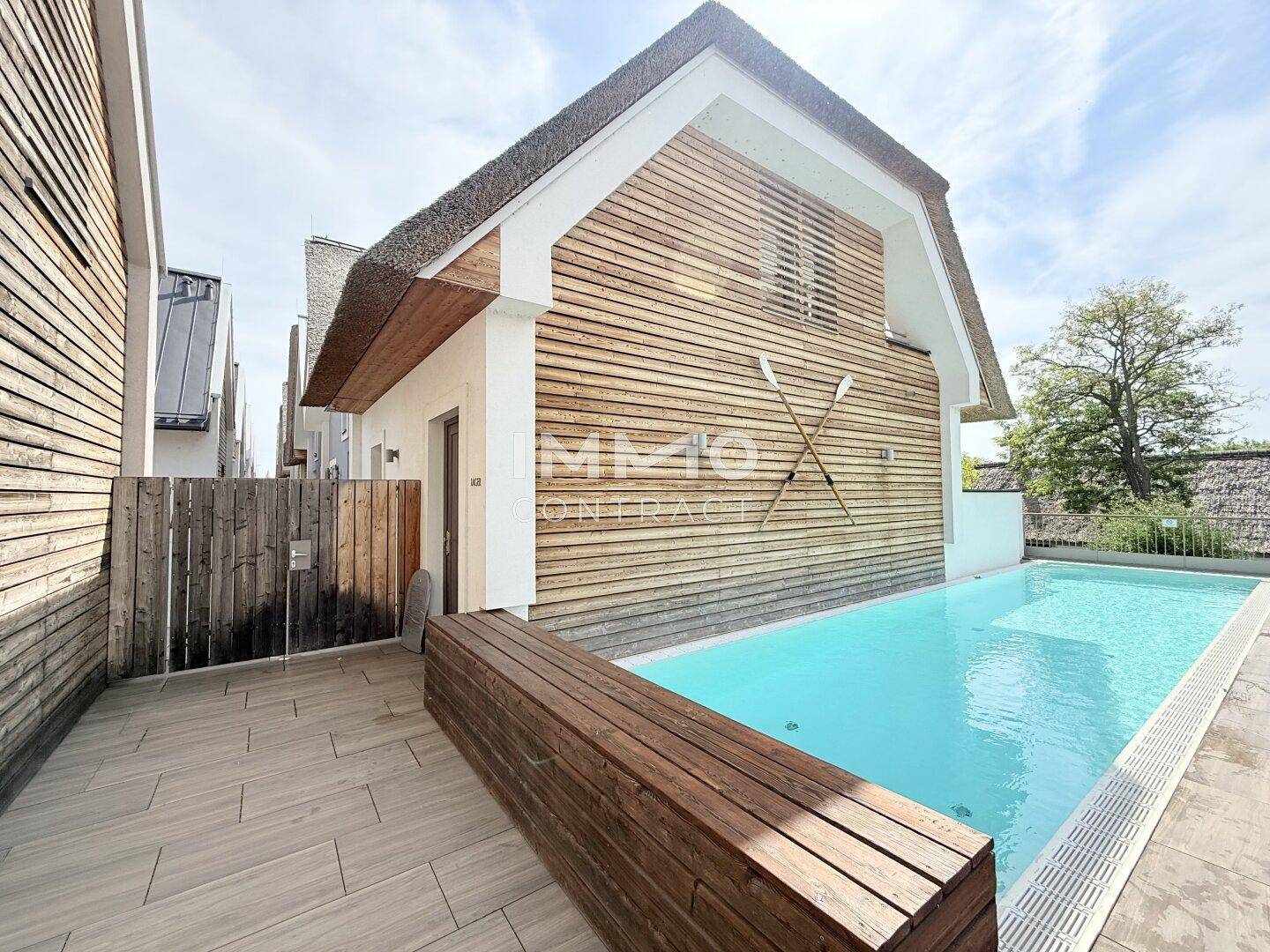 Außenbereich mit privatem Pool und Holzterrasse, angrenzend an ein modernes Gebäude.
