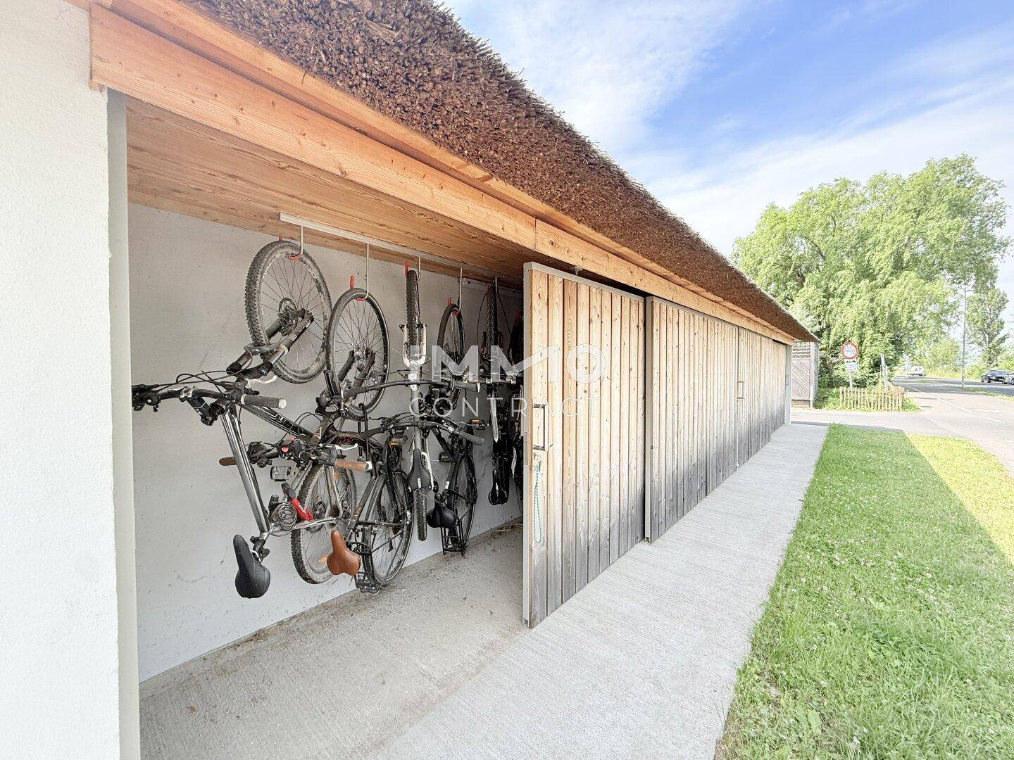 Überdachter Fahrradabstellplatz mit mehreren Fahrrädern und Holzverkleidung.