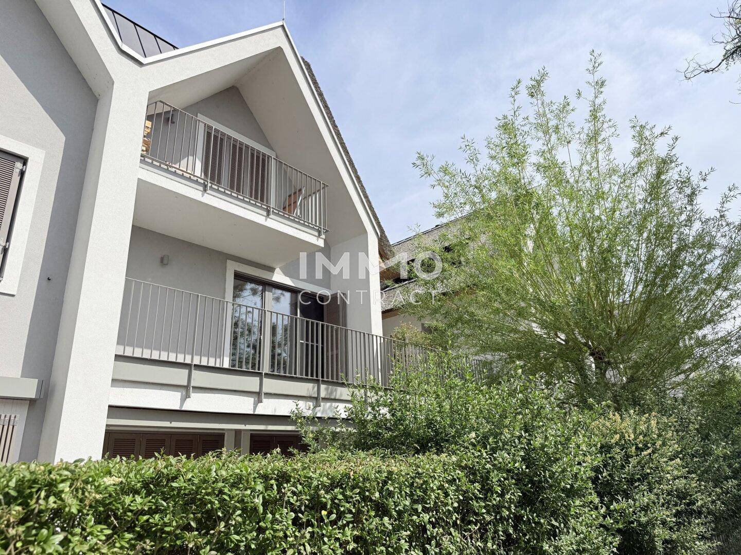 Moderne Architektur mit Balkonen und grüner Bepflanzung im Vordergrund.